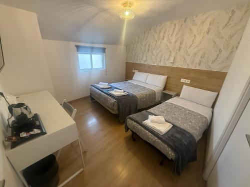 Una pequeña habitación con dos camas y un escritorio. en Hostal Esparteros, en Madrid