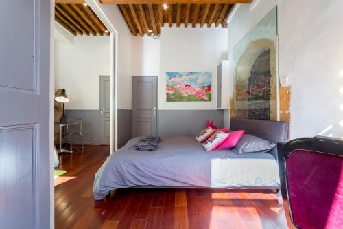 a bedroom with a bed with pink pillows on it at Le Duplex de Fourvière in Lyon