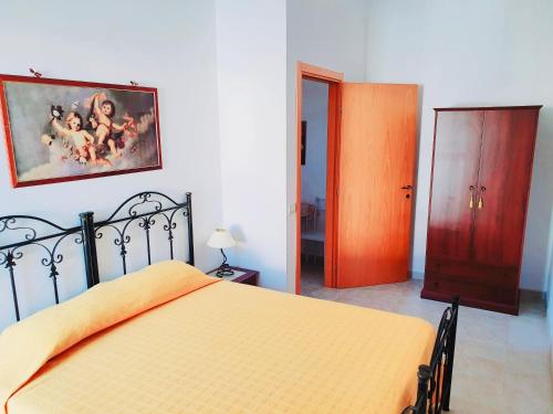 a bedroom with a bed and a painting on the wall at Il Carrubo&Castagno Casette vacanza in Villaggio Azzurro