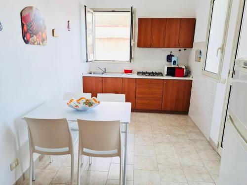 a kitchen with a white table and chairs in a room at Il Carrubo&Castagno Casette vacanza in Villaggio Azzurro