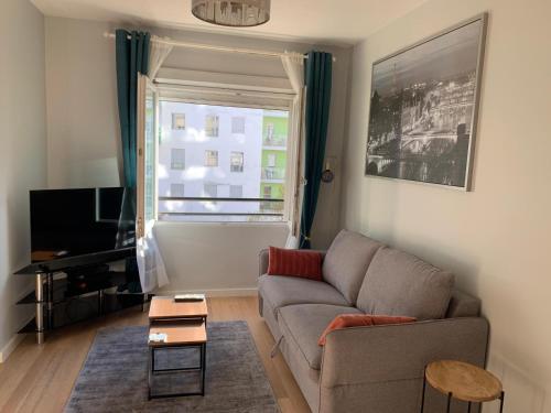 a living room with a couch and a window at Appartement cosy - Paris La Défense in Courbevoie
