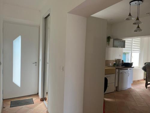 une cuisine aux murs blancs et un couloir avec une porte dans l'établissement Latour des Sens, à Pont-Saint-Esprit