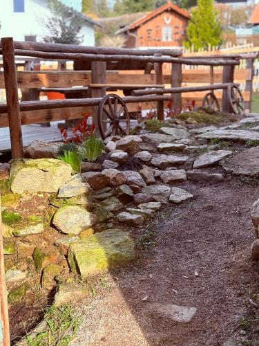 a stone wall with a wooden fence and a wooden bench at Zum oidn Schmie Haus in Pemfling