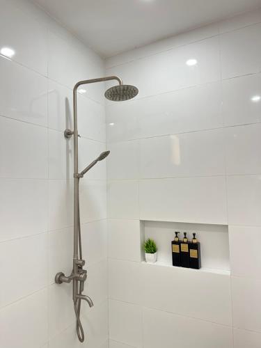 a shower in a bathroom with white tiles at Casa Rama Hotel Tagaytay in Tagaytay