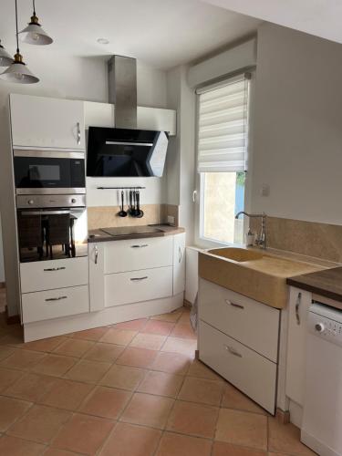 une cuisine avec des placards blancs et une grande fenêtre dans l'établissement Latour des Sens, à Pont-Saint-Esprit