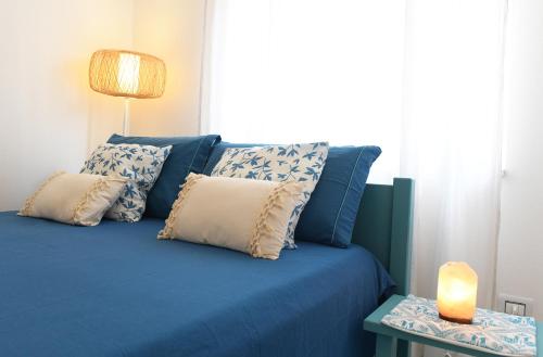 a blue bed with pillows and a candle on a table at Casa MaRì, a due passi dal mare in Alghero
