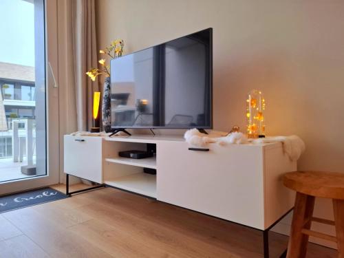 a living room with a tv on a white dresser at Villa Creole 0308 Luxe appartement met verwarmd zwembad Nieuwpoort Jachthaven in Nieuwpoort