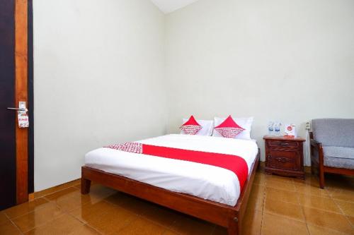a bedroom with a bed with a red and white blanket at Hotel O Paviliun Permata in Solo