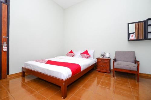 a bedroom with a bed and a chair at Hotel O Paviliun Permata in Solo