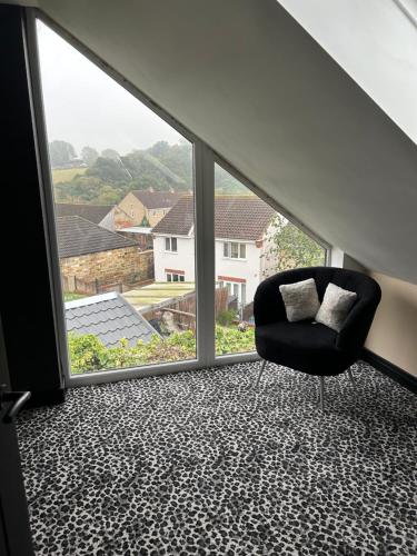 a black chair in a room with a large window at The Cleveland Retreat in Boosbeck