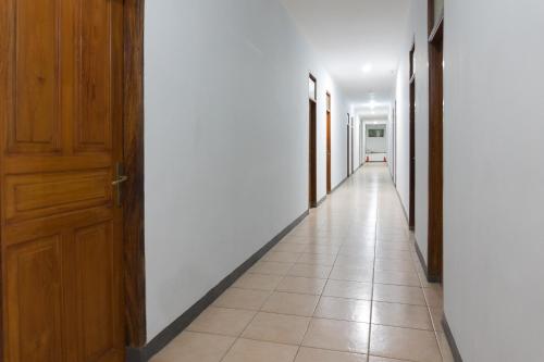 a hallway with white walls and a wooden door at Hotel O Pantai Jaya in Pangandaran