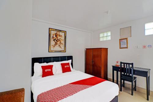 a bedroom with a bed with red pillows and a desk at Hotel O Gusti Residence in Dalung
