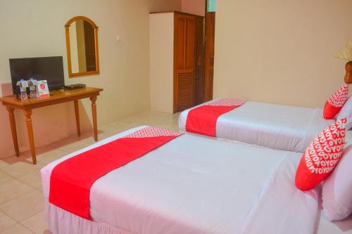 a hotel room with two beds and a table at Hotel O Pantai Jaya in Pangandaran