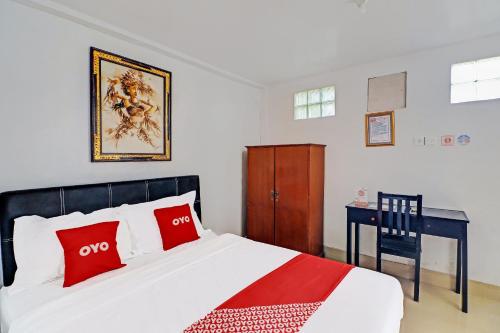 a bedroom with a bed with red pillows and a desk at Hotel O Gusti Residence in Dalung