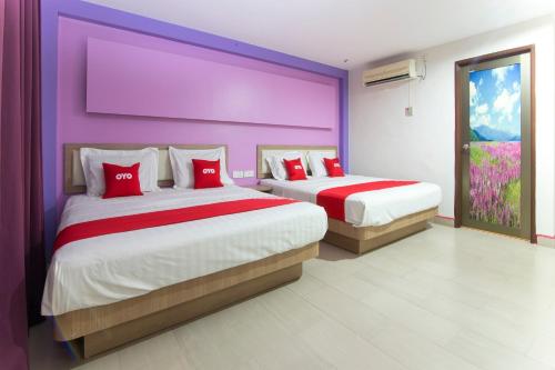 two beds in a room with purple and purple walls at Valley View Hotel in Lumut