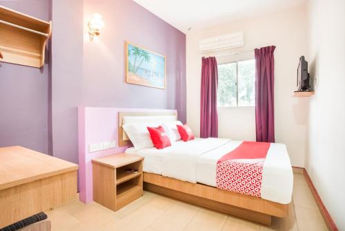 a bedroom with purple walls and a bed with red pillows at Valley View Hotel in Lumut