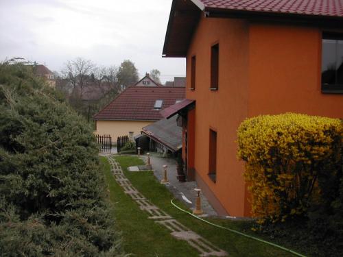 an orange building with a garden next to a house at Penzion U Slunce in Jaroměř