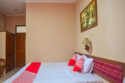 a bedroom with a bed with red and white pillows at Hotel O Pantai Jaya in Pangandaran