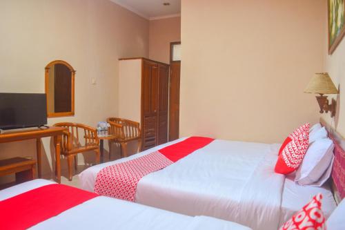 a bedroom with two beds and a desk with a computer at Hotel O Pantai Jaya in Pangandaran