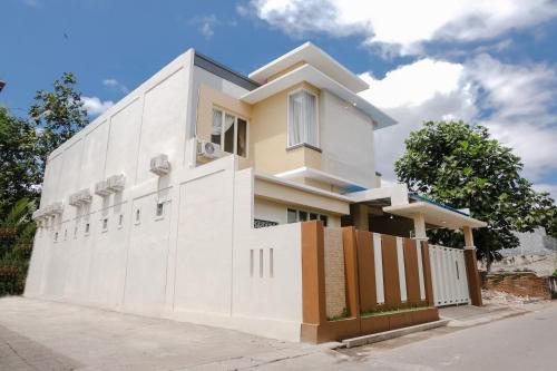 a white house with a fence in front of it at Hotel O Antosa Family Residence in Jember