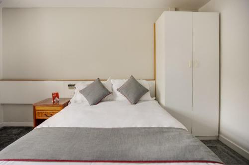 a bedroom with a white bed and a white cabinet at OYO Glenpark Hotel, Ayr Central in Ayr