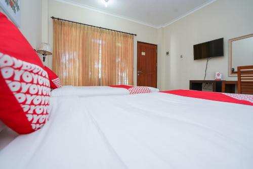 a bedroom with a large bed with a red blanket at Capital O 1430 Hotel Ratna Syariah in Probolinggo