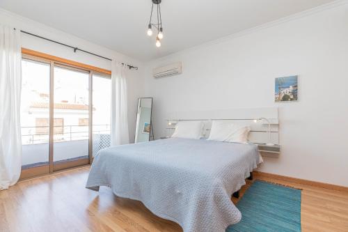 a white bedroom with a bed and a large window at Apartment Perola-superb Base In Historical Centre in Tavira