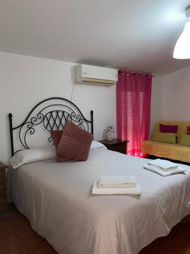 a bedroom with a large white bed with red curtains at Casa Cris in Aracena