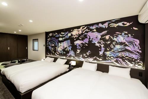 two beds in a room with a painting on the wall at Randor Residence Kyoto Nijo Castle in Kyoto