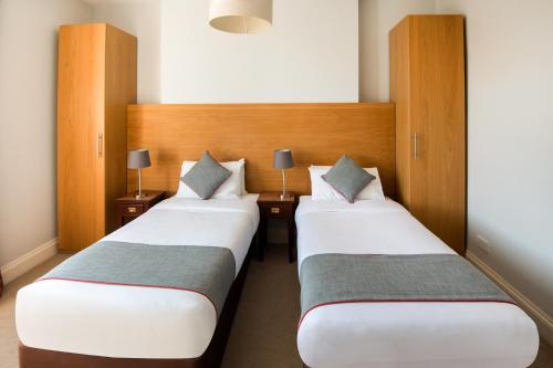 two beds in a hotel room with two lamps at The Regency, Clifton Bristol in Bristol