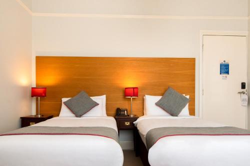 two beds in a hotel room with two lamps at The Regency, Clifton Bristol in Bristol