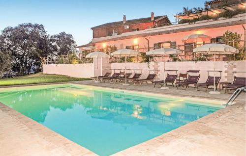 a swimming pool with chairs and umbrellas next to a building at Amazing Apartment In Montalto Di Castro in Montalto di Castro
