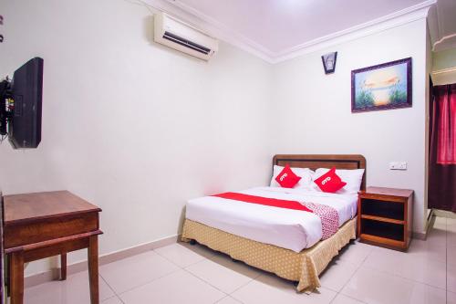 a bedroom with a bed with red pillows and a desk at Hotel O Casavilla Hotel in Batu Caves