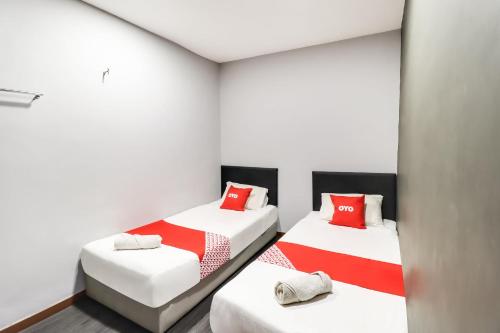 two beds in a room with white walls and red pillows at OYO 89381 Moonnight Hotel in Batu Caves