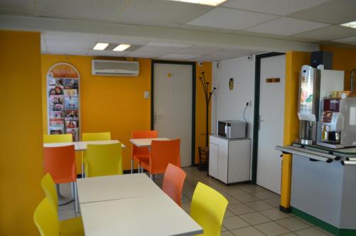a dining room with tables and chairs and yellow walls at Premiere Classe Chambery in Chambéry