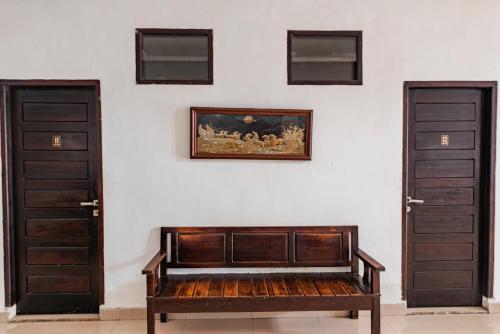 a wooden bench sitting in front of two doors at Hotel O Kambang Iwak Area Near Kambang Iwak Park Formerly Kerangga in Palembang