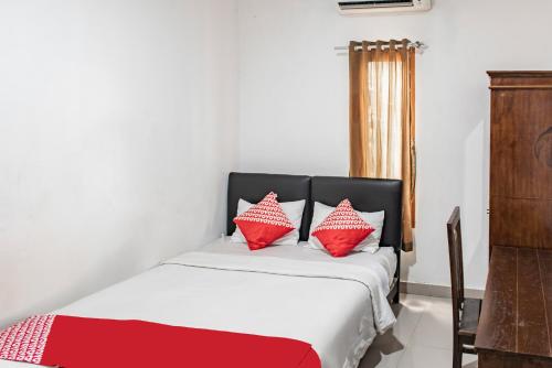 a bedroom with a bed with red and white pillows at Hotel O Kambang Iwak Area Near Kambang Iwak Park Formerly Kerangga in Palembang