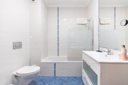 a white bathroom with a toilet and a bath tub at Apartment Perola-superb Base In Historical Centre in Tavira