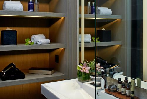 a bathroom with a sink and a shelf with towels at VE Hotel & Residence in Kuala Lumpur
