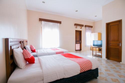 a bedroom with two beds with red and white pillows at Hotel O Edotel Smkn 1 Pacet Syariah in Puncak