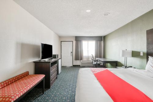 a hotel room with a bed and a desk and a television at OYO Hotel Rosenberg TX I-69 in Rosenberg