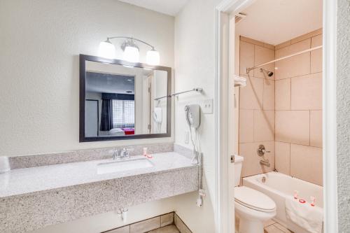 a bathroom with a sink and a toilet and a mirror at OYO Hotel Rosenberg TX I-69 in Rosenberg