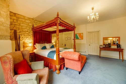 a bedroom with a canopy bed and two chairs at OYO Bailbrook Lodge, Bath in Bath