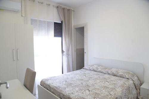 a white bedroom with a bed and a window at Prestige Affittacamere Paestum in Stazione di Paestum