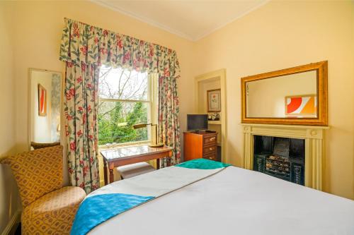 a bedroom with a bed and a fireplace and a window at OYO Bailbrook Lodge, Bath in Bath