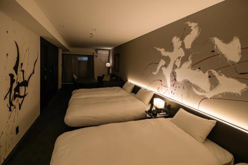 two beds in a hotel room with a map on the wall at Randor Residence Kyoto Nijo Castle in Kyoto