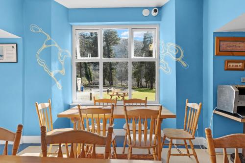 a dining room with a table and chairs and a window at Glendalough International Youth Hostel in Laragh