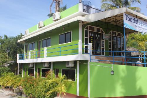 a green building with a balcony and palm trees at Vacation House in Klong Muang Beach