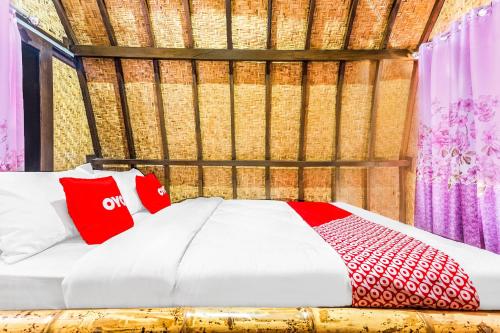 a bedroom with a bed with red and white pillows at Hotel O Telone Bungalow in Palebah