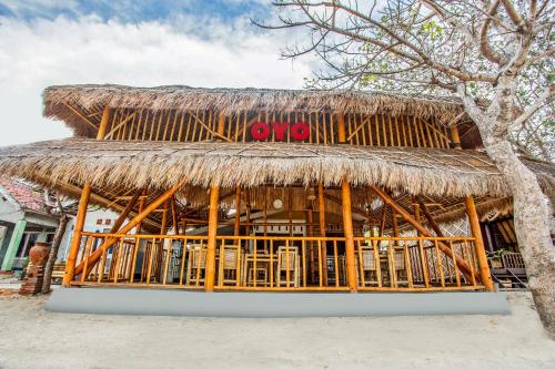 a restaurant with a thatched roof on the beach at Hotel O Telone Bungalow in Palebah